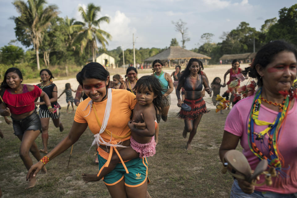 In this Sept. 3, 2019 photo, villagers run as part of a ritual during a meeting of Tembé tribes in Tekohaw indigenous reserve, Para state, Brazil. Some had travelled long distances on dirt roads that cut through the lush jungle, or in boats along a muddy brown tributary of the Amazon River. (AP Photo/Rodrigo Abd)