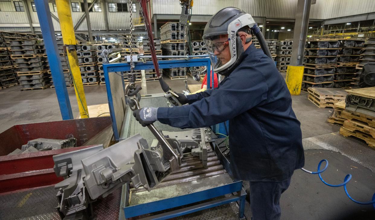 A work moves a steering column support for a John Deere tractor before automated grinding work is done Thursday, May 18, 2023 at Waupaca Foundry in Waupaca, Wis. The foundry has seen an increase in business from companies seeking to lessen their reliance on parts made in China and India.