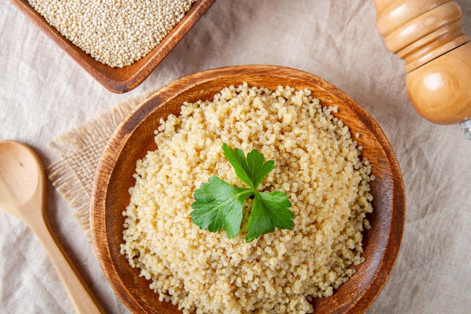 cooked quinoa in a wooden plate on the table, top view