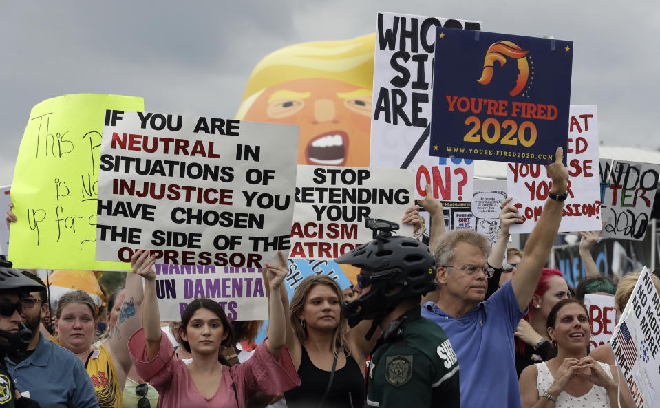 Protestors hold up anti President Donald Trump signs during a rally Tuesday, June 18, 2019, in Orlando, Fla. A large group of protestors were holding a rally near where Trump was announcing his re-election campaign. (AP Photo/Chris O'Meara)