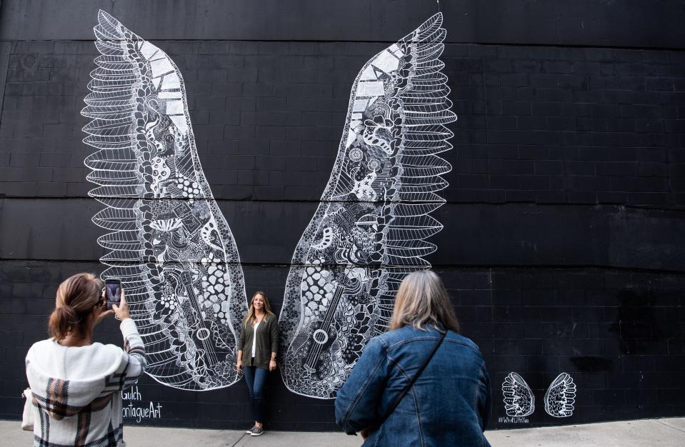 Visitors snap photos by the What Lifts You angel wings mural on 11th Avenue in Nashville's Gulch neighborhood.