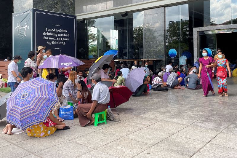 People line up outside a bank to withdraw cash, in Yangon