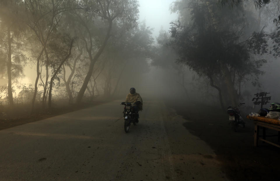 A motorcyclist drives as heavy fog reduces visibility, in Peshawar, Pakistan, Sunday, Jan. 1, 2023. (AP Photo/Muhammad Sajjad)