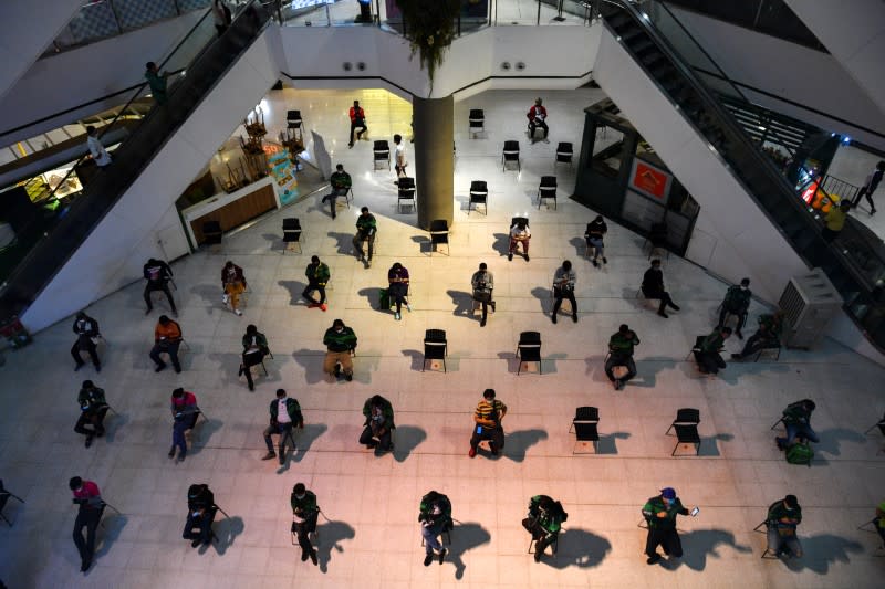 Staff of food delivery companies sit on social distancing chairs due to coronavirus disease (COVID-19) outbreak, as they wait for their costumers' orders at a department store in Bangkok