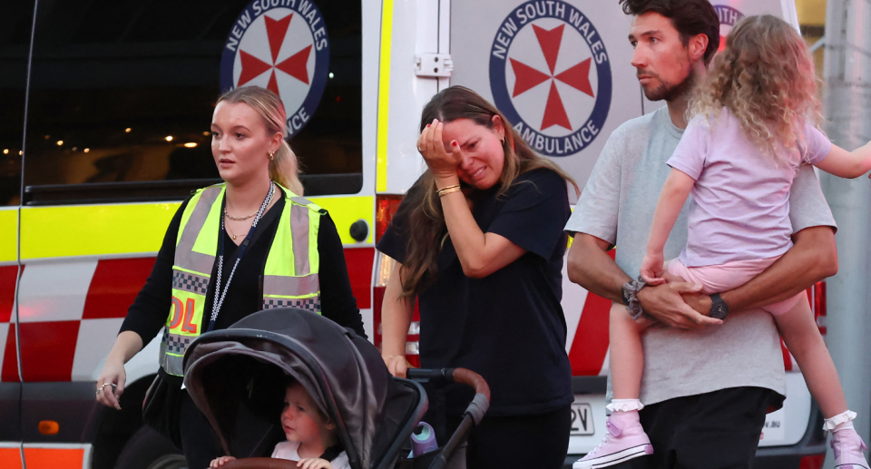 A paramedic talking with a man and women and two children.