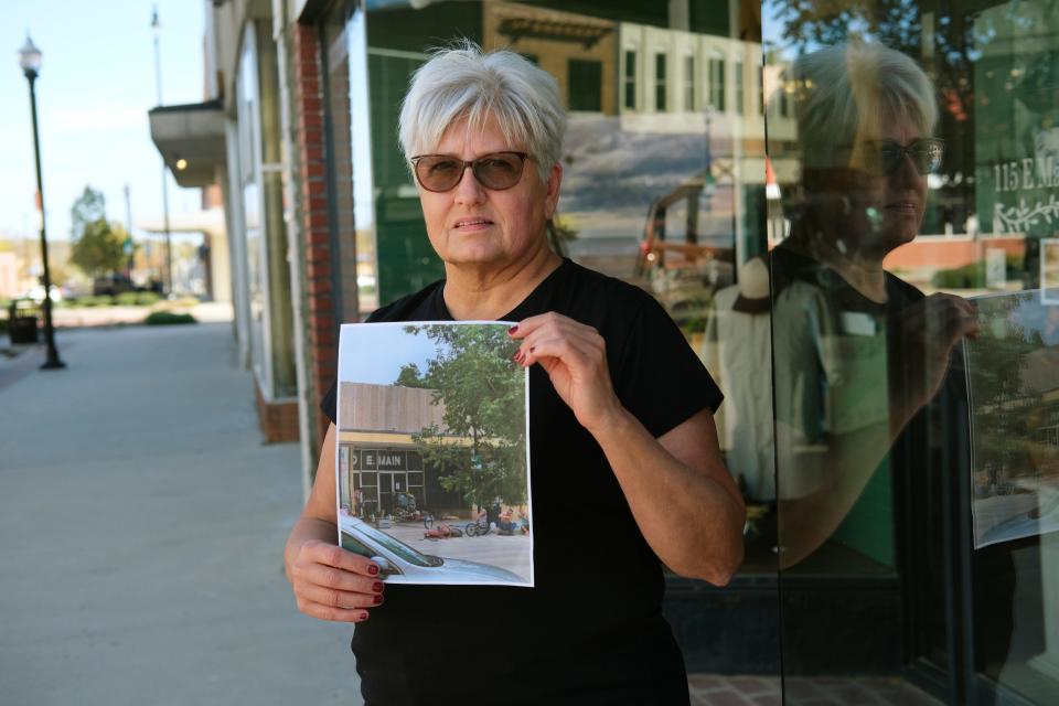 Theresa Cody, Uncommon Threads owner who started a  "downtown watch" group with cameras, holds a photo Nov. 6 of homeless people who had taken over the sidewalks downtown a year ago.