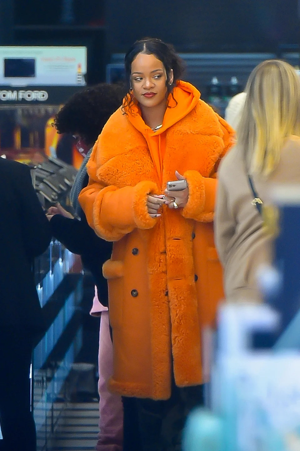 Rihanna wears a huge orange coat in a Sephora