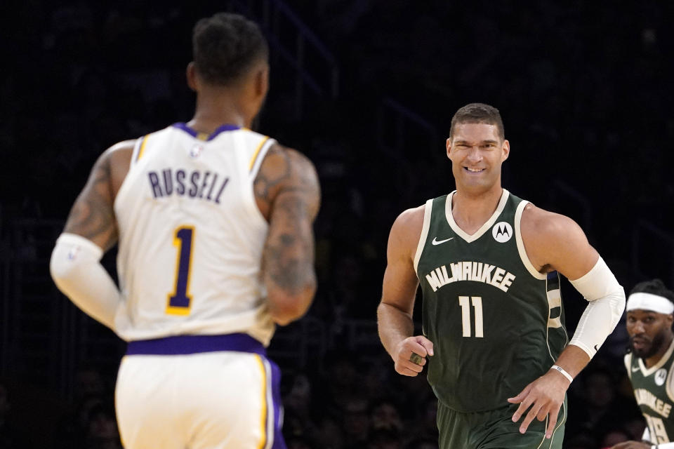 Milwaukee Bucks center Brook Lopez, right, smiles at Los Angeles Lakers guard D'Angelo Russell after Russell made a difficult shot during the first half of an NBA preseason basketball game Sunday, Oct. 15, 2023, in Los Angeles. (AP Photo/Mark J. Terrill)