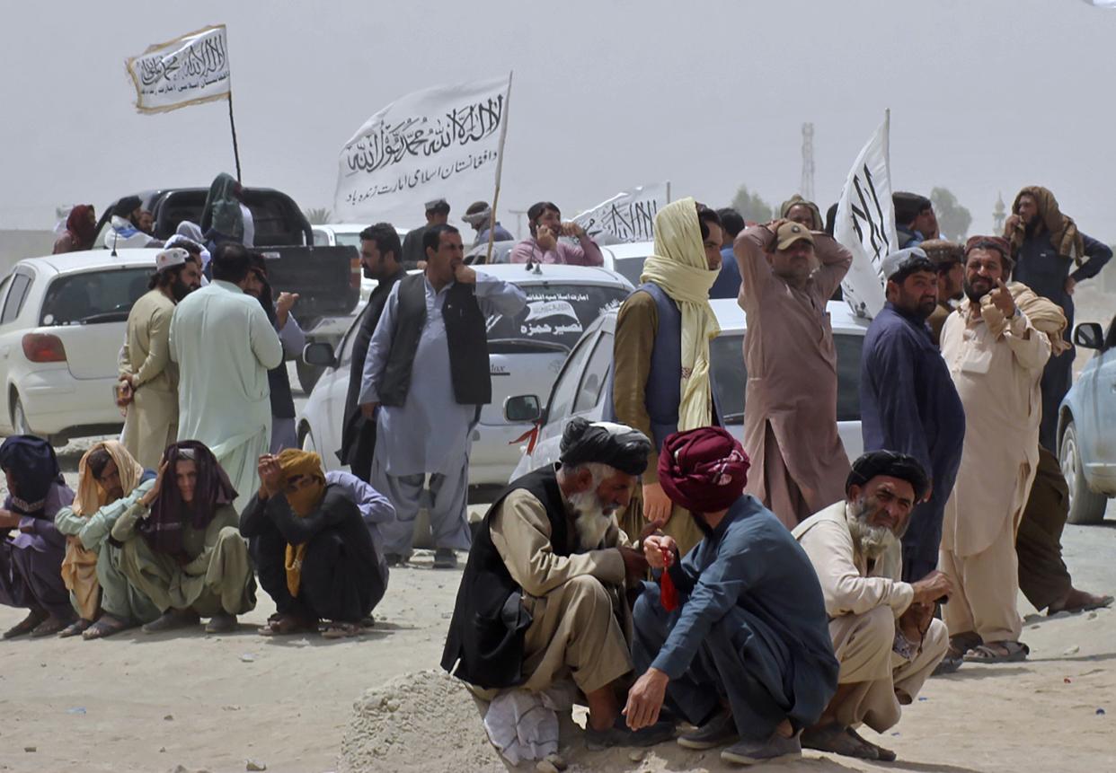 People near the Taliban's signature white flags wait for the arrival of their relatives, who were reportedly released from prison by the Taliban in Afghanistan, at a border crossing point, in Chaman, Pakistan, Tuesday, Aug. 17, 2021.