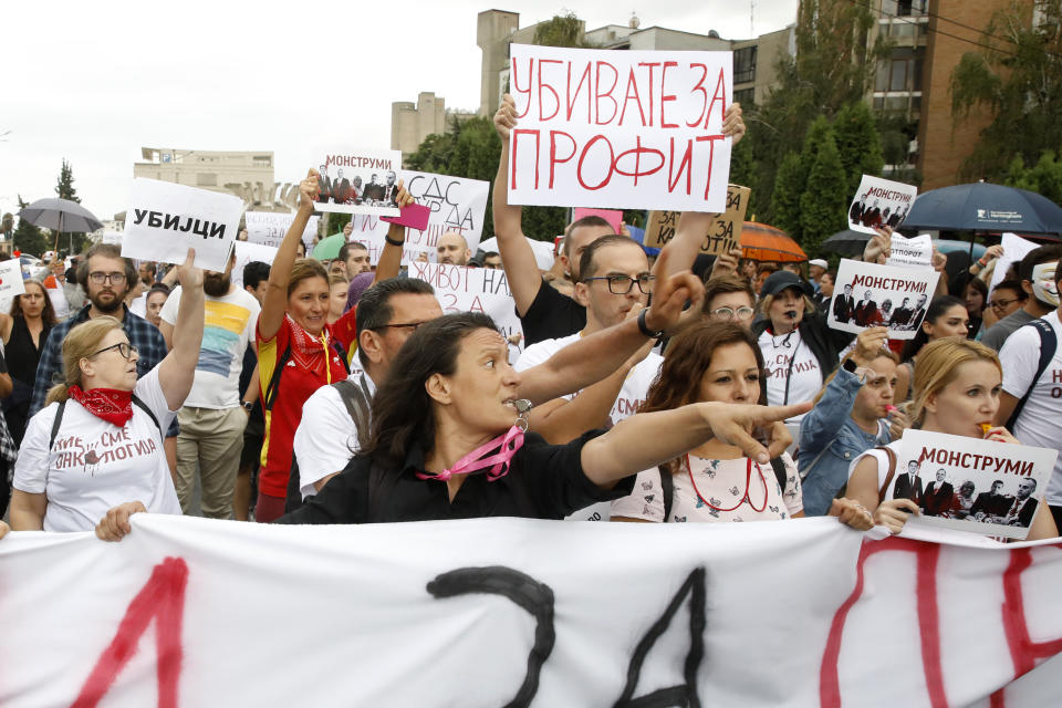 Protestors carry banners and chant "Murderers" in front of the Government building in Skopje, North Macedonia, on Monday, Sept. 4. 2023. Thousands have gathered late on Monday in front of the government in North Macedonia's capital Skopje to protest on scandal that broke after media reported that employees in the state running Clinic of Oncology allegedly were selling on a black market a million of dollars' worth clinic supply of drugs needed for cancer treatment. The banner atop reads in Macedonian "You are killing for profit". (AP Photo/Boris Grdanoski)