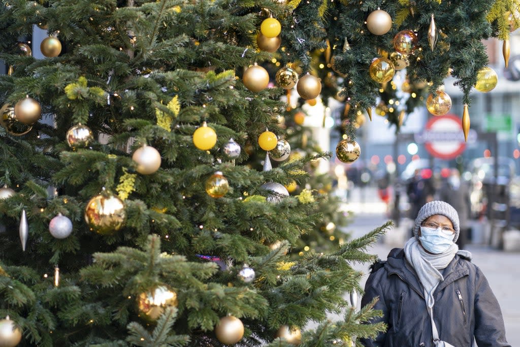 A woman wears a mask as she walks past Christmas decorations in London’s Knightsbridge (Dominic Lipinski/PA) (PA Wire)