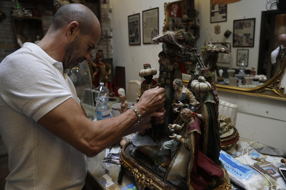 Nativity Scene craftsman Marco Ferrigno works in his shop in Via San Gregorio Armeno street in downtown Naples, Italy Wednesday, Sept. 18, 2019. “One of the first figurines we made was of Diego Armando Maradona and you can imagine how many we sold. Still today, it sells a lot,” said craftsman Marco Ferrigno, who runs the most prominent shop on the street. (AP Photo/Gregorio Borgia)