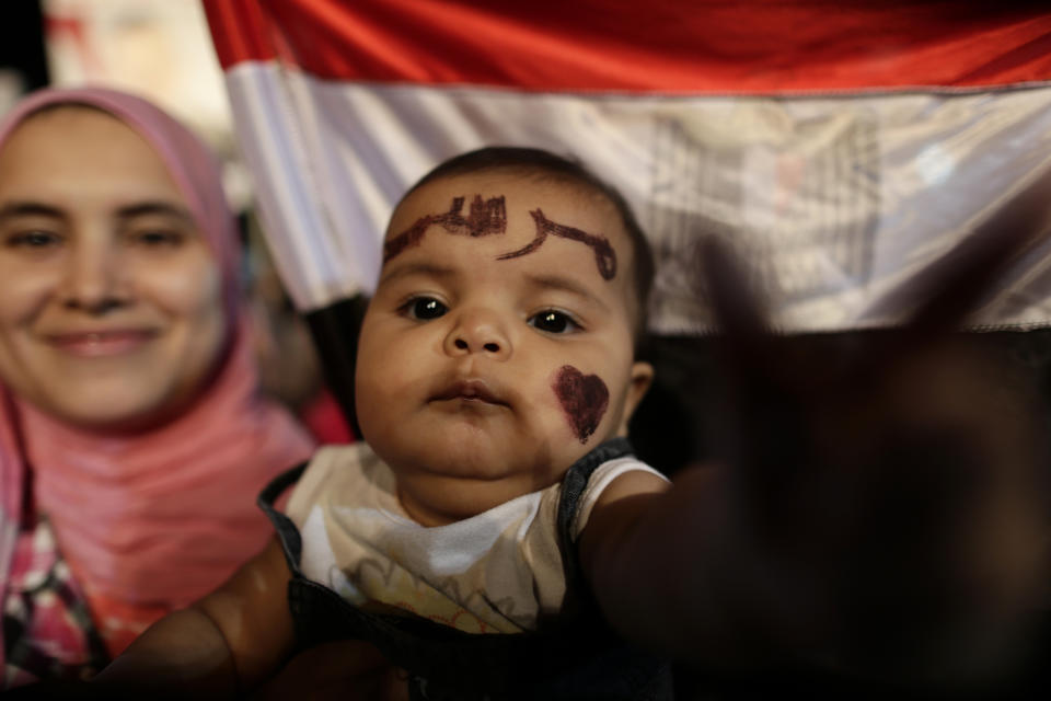 Qurbah, six months old, with Arabic that reads, "Morsi," painted on her face, attends a demonstration with her mother outside Rabaah al-Adawiya mosque, where they have installed a camp and hold daily rallies at Nasr City, in Cairo, Egypt, Wednesday, July 31, 2013. (AP Photo/Hassan Ammar)