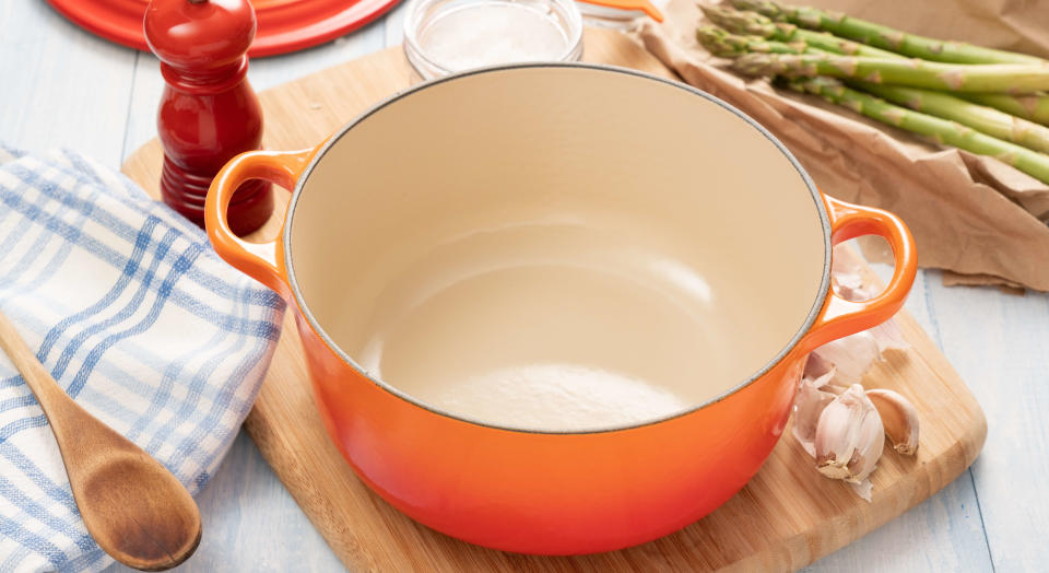 Empty range Dutch oven surrounded by food and cooking implements