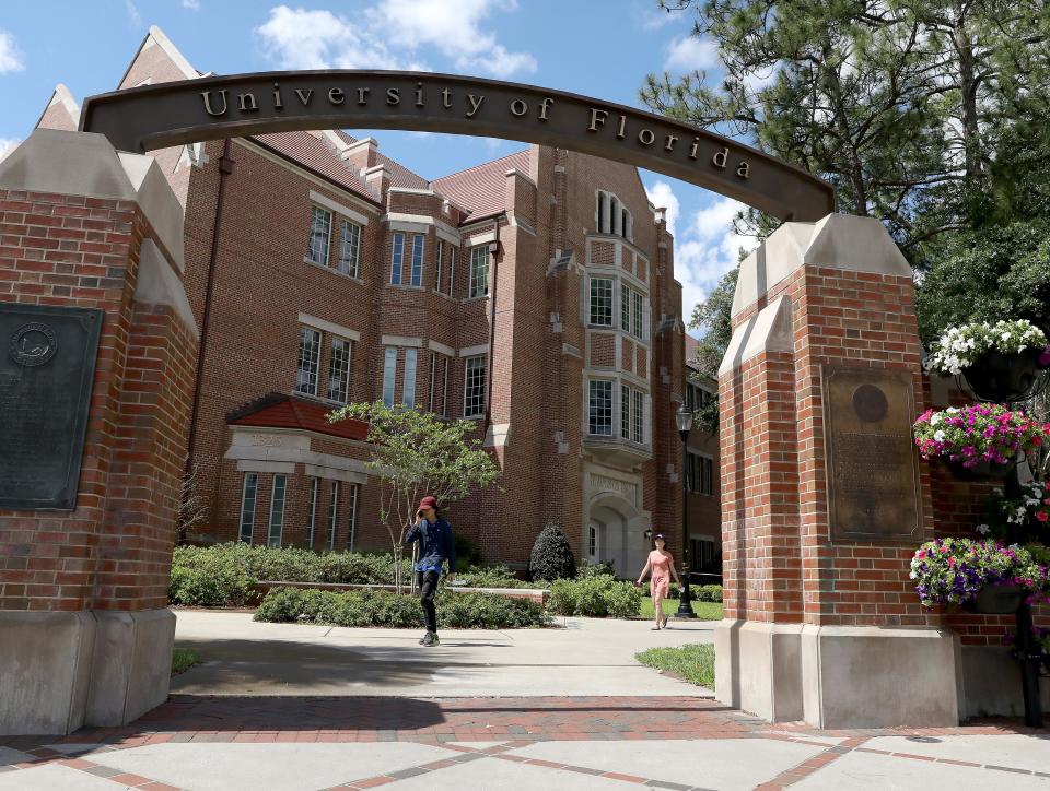 People walk toward the arch entrance to the University of Florida at the corner of University Avenue and 13th Street