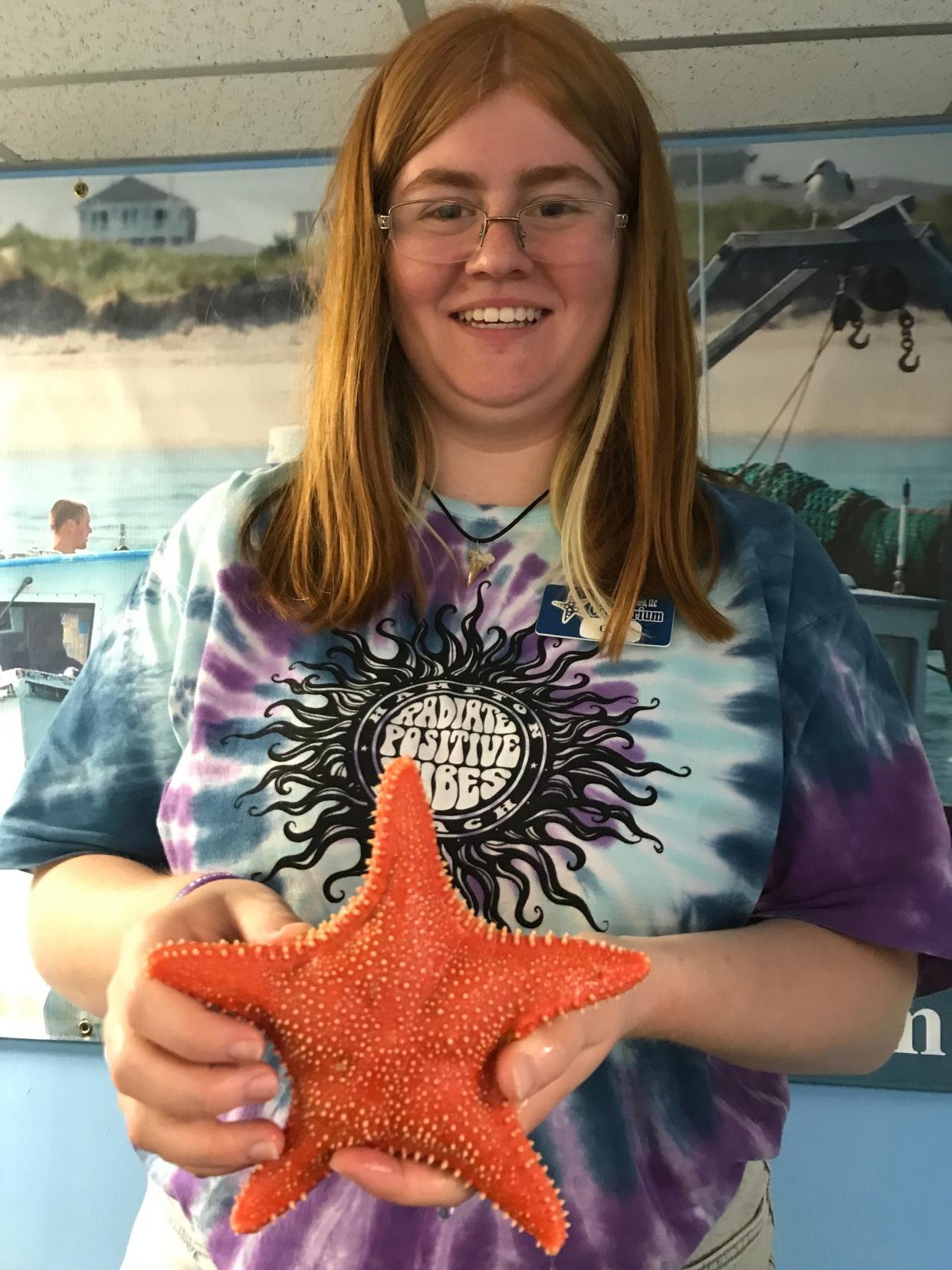 Catriel Conroy, who is studying marine science at the University of New England, holds up a red mud star at the Hampton Beach Oceanarium.