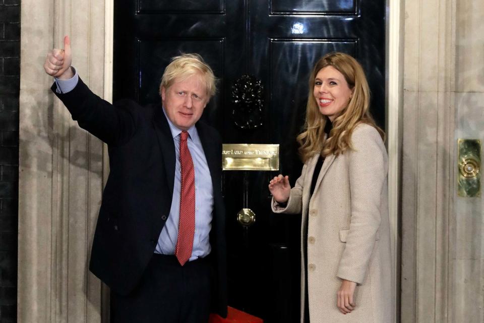 Boris Johnson and his partner Carrie Symonds wave from the steps of number 10 Downing Street (AP)