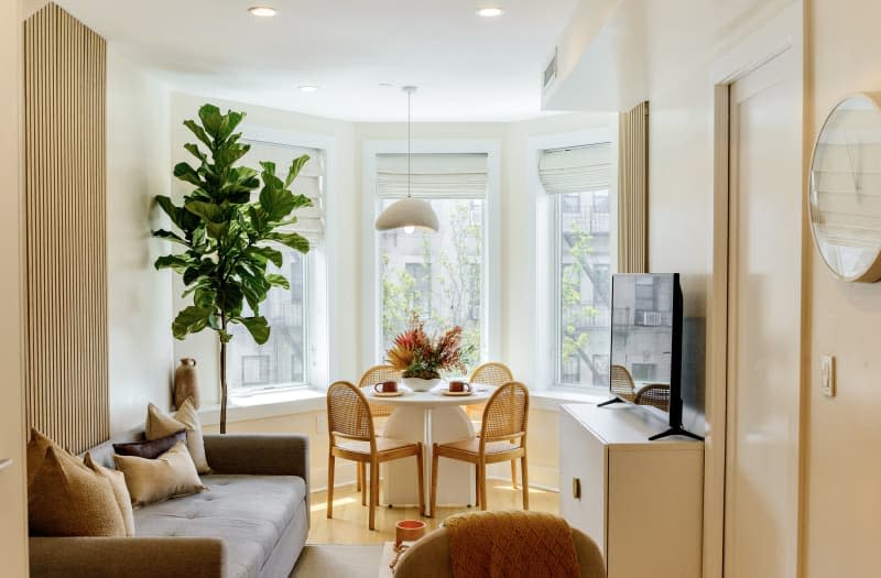 white living room with grey sofa and wood slat wall detail. Dining room visible behind