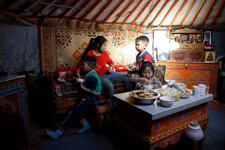 Ganbileg Gankhuyag, 7, and Namuun, 5, have tea next to others playing cards in their Mongolian ger in Tov province outside Ulaanbaatar, Mongolia January 30, 2019. Picture taken January 30, 2019. REUTERS/B. Rentsendorj