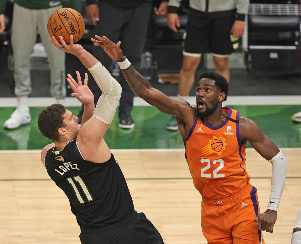 Deandre Ayton puts his arm up to defend a shot by Brook Lopez.