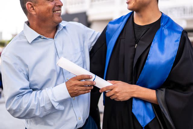 <p>FG Trade Latin/Getty</p> Young graduate man talking with his father on the graduation