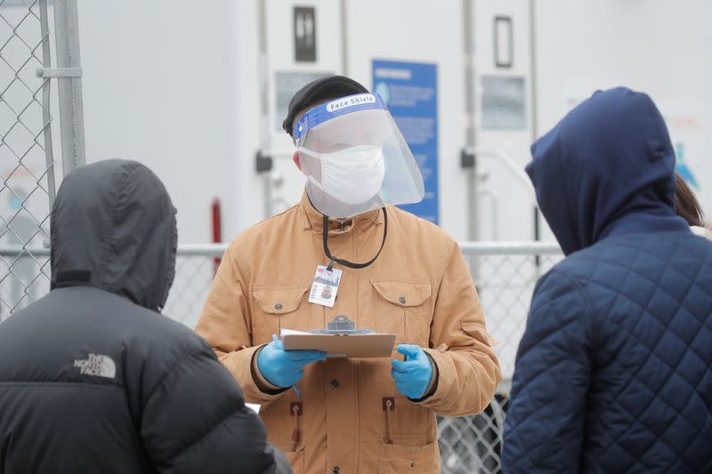 People speak to a healthcare worker while in line to receive a dose of the coronavirus disease (COVID-19) vaccine at a 24 hour vaccination center at the Brooklyn Army Terminal in Brooklyn, New York