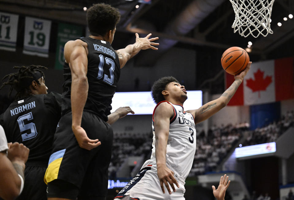 UConn forward Jaylin Stewart (3) makes a basket past Marquette guard Tre Norman (5) and Marquette forward Oso Ighodaro (13) in the first half of an NCAA college basketball game, Saturday, Feb. 17, 2024, in Hartford, Conn. (AP Photo/Jessica Hill)