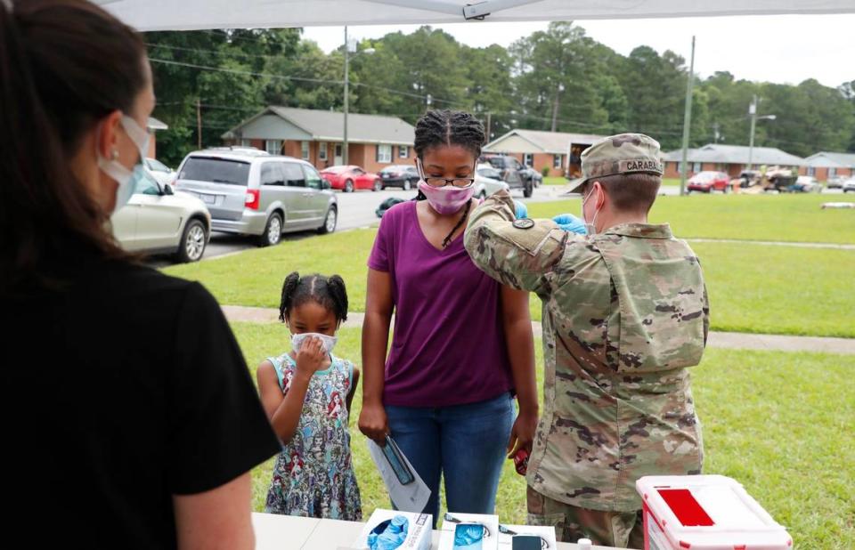 Sgt. Sabrina Caraballo with the North Carolina Army National Guard gives Briona Davis a COVID-19 vaccine shot during a pop up vaccine clinic in the Smithfield Housing Authoritys subdivision of Woodall Heights in Smithfield, N.C. Tuesday, June 8, 2021. With Davis is her daughter, Rayona Jones.