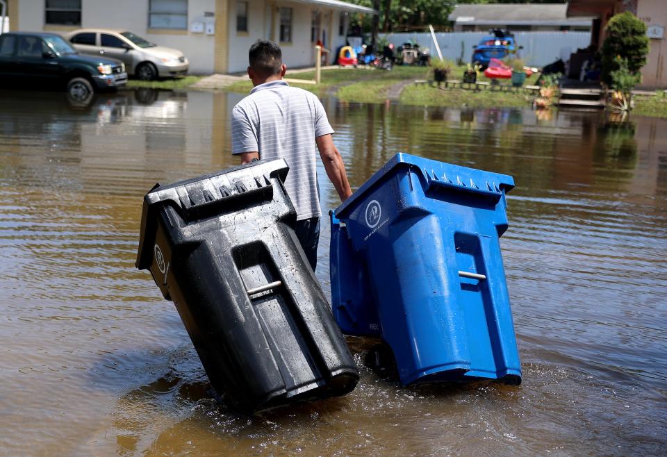 Luis Calderon retrieves trash bins that floated away when flood waters inundated the area on April 14, 2023 in Fort Lauderdale, Florida. Nearly 26 inches of rain fell on Fort Lauderdale over a 24-hour period causing flooding.