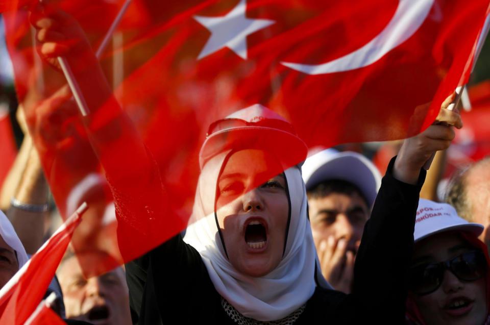 People wave flags as they wait for Turkish President Tayyip Erdogan