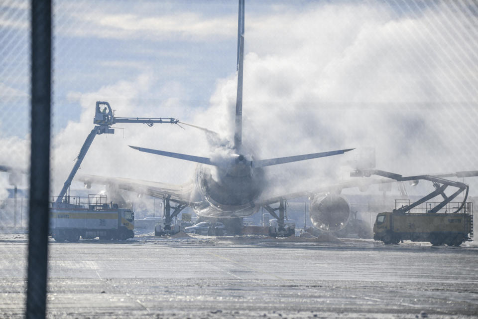 A passenger plane is cleared of ice in Munich Airport, Germany, Tuesday Dec. 5, 2023. After an interruption of several hours due to the weather conditions, Munich Airport has resumed operations. (Jason Tschepljakow/dpa via AP)