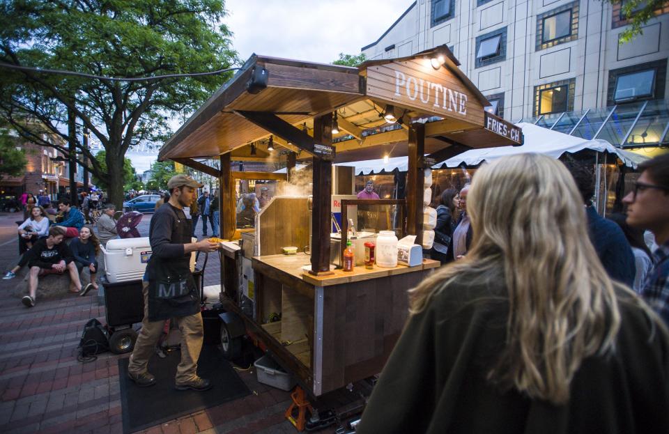 Joe Collier serves customers waiting to be served from the Maudite Poutine food cart on Church Street in Burlington on Friday, June 2, 2017.