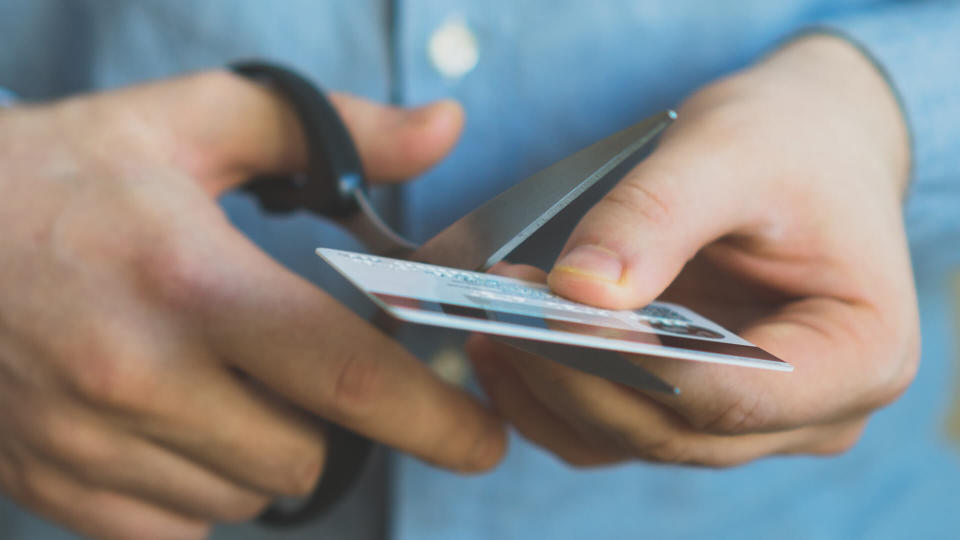 Man cutting credit card with scissors.