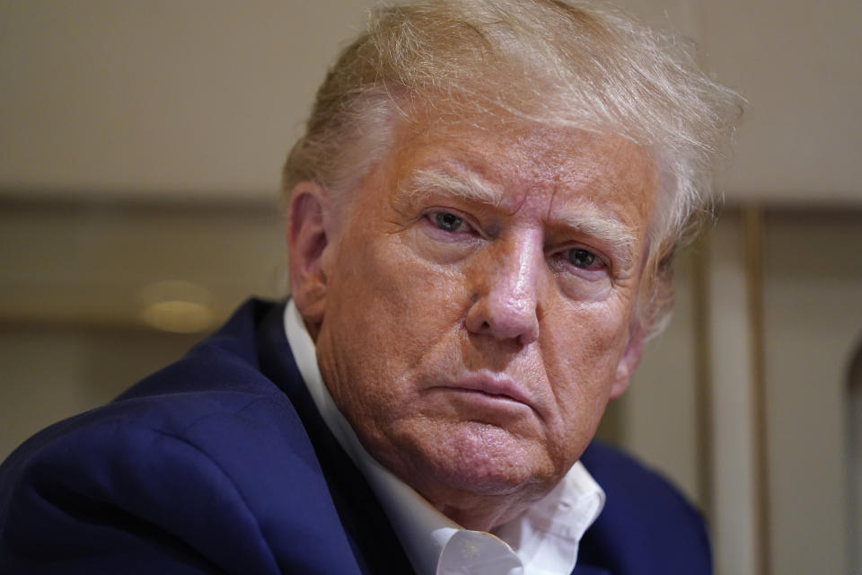 FILE - Former President Donald Trump listens as he speaks with reporters while in flight on his plane after a campaign rally at Waco Regional Airport, in Waco, Texas, March 25, 2023, while en route to West Palm Beach, Fla. (AP Photo/Evan Vucci, File)