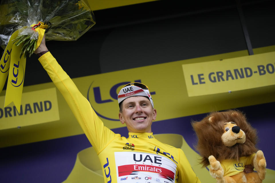 Slovenia's Tadej Pogacar, wearing the overall leader's yellow jersey, celebrates on the podium after the eighth stage of the Tour de France cycling race over 150.8 kilometers (93.7 miles) with start in Oyonnax and finish in Le Grand-Bornand, France,Saturday, July 3, 2021. (AP Photo/Christophe Ena)