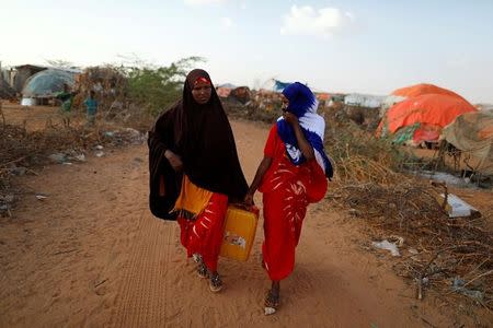 Zeinab, 14, (R) and her sister Habiba, 29, carry a jerrycan filled with water as they walk toward their shelter at a camp for internally displaced people from drought hit areas in Dollow, Somalia April 3, 2017. REUTERS/Zohra Bensemra