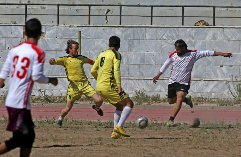 Syrians take part in a football match on April 16, 2018 between local teams at a stadium in Raqa that the Islamic State group once used as a prison