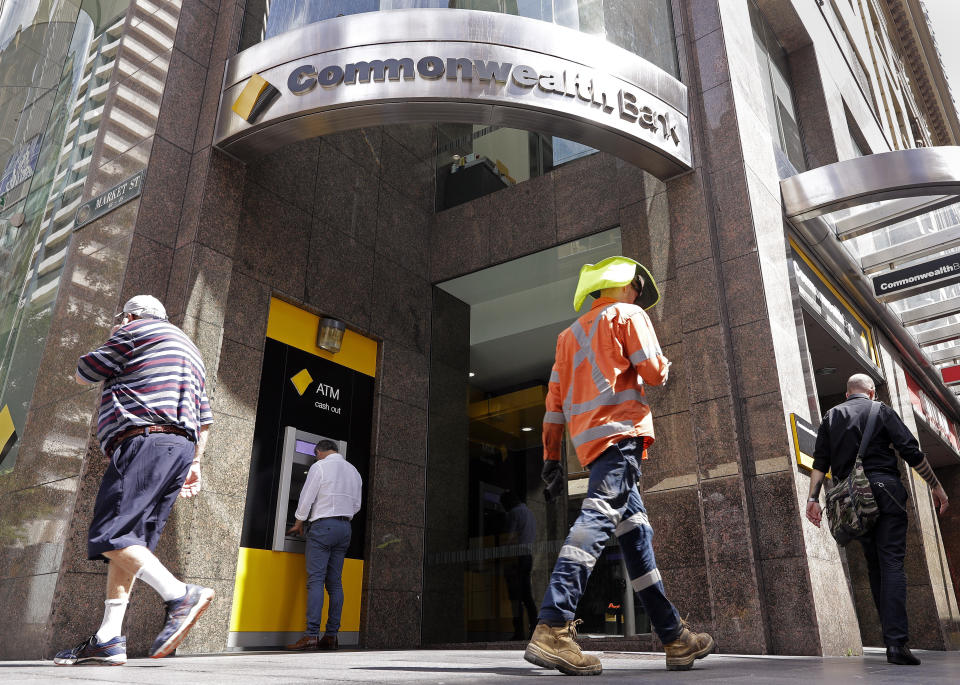 People pass by a Commonwealth Bank branch in Sydney, Wednesday, Feb. 6, 2019. The Commonwealth Bank of Australia recorded a drop in statutory net profit in its latest half-year to 4.6 billion Australian dollars ($3.3 billion) as the nation's biggest lender was hit by costs for misconduct as well as lower profit margins and a downturn in the housing market. (AP Photo/Rick Rycroft)