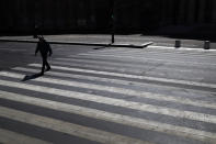 A man crosses an empty street during a nationwide confinement to counter the Covid-19, in Paris, Saturday, April 4, 2020. The new coronavirus causes mild or moderate symptoms for most people, but for some, especially older adults and people with existing health problems, it can cause more severe illness or death. (AP Photo/Christophe Ena)