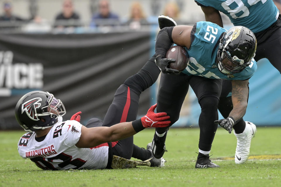 Jacksonville Jaguars running back James Robinson (25) slips past the tackle of Atlanta Falcons linebacker James Vaughters (93) during the first half of an NFL football game, Sunday, Nov. 28, 2021, in Jacksonville, Fla. (AP Photo/Phelan M. Ebenhack)