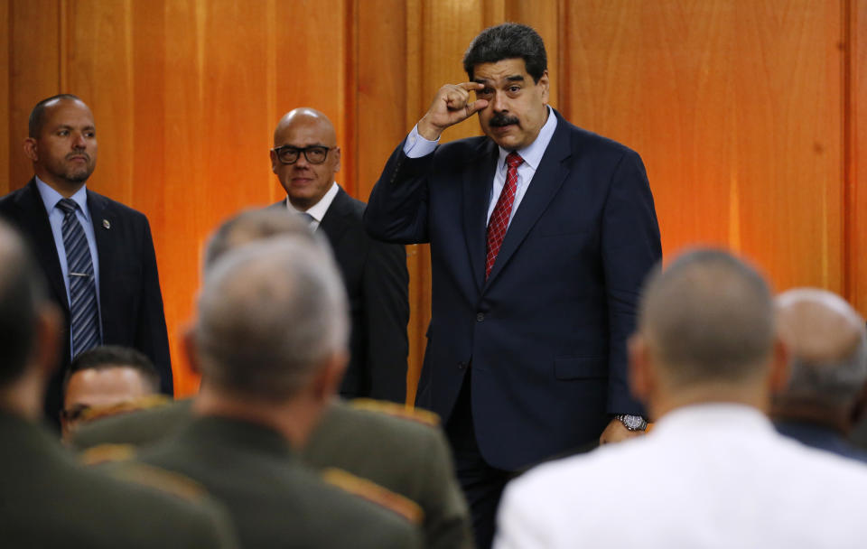Venezuelan President Nicolas Maduro gestures to military leaders to keep their eyes open, at the end of his press conference inside the presidential palace in Caracas, Venezuela, Friday, Jan. 25, 2019. Even as Venezuelans fill the streets rallying behind opposition leader Juan Guaido and the list of foreign nations recognizing him as the country’s rightful president grows, the top members of the all-important military are sending a different message: Forget about it.(AP Photo/Ariana Cubillos)
