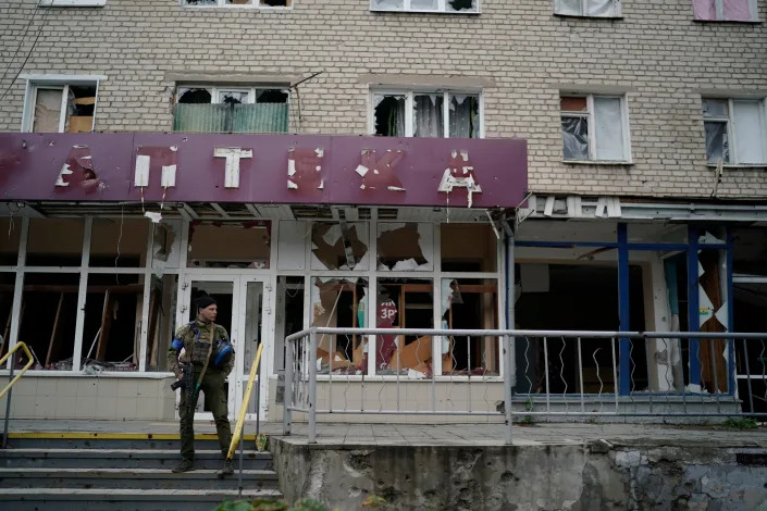 A Ukrainian serviceman stands in front of a damaged building in the recaptured area of Izium, Ukraine, Wednesday, Sept. 14, 2022.