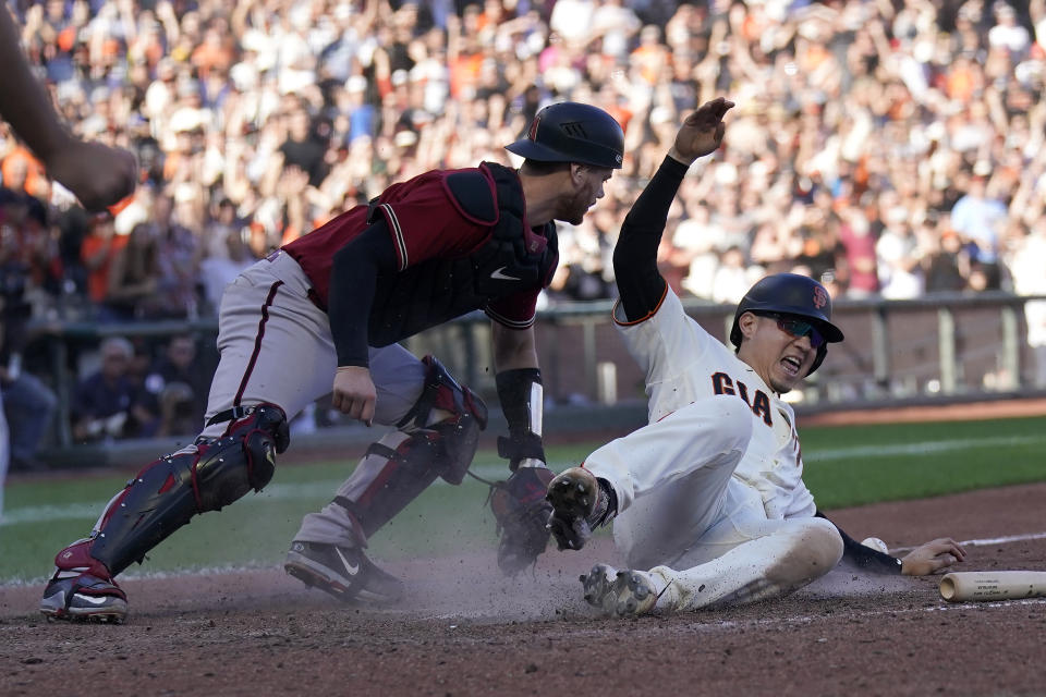 San Francisco Giants' Wilmer Flores, right, slides home to score the winning run against Arizona Diamondbacks catcher Carson Kelly during the 10th inning of a baseball game in San Francisco, Sunday, Oct. 2, 2022. (AP Photo/Jeff Chiu)