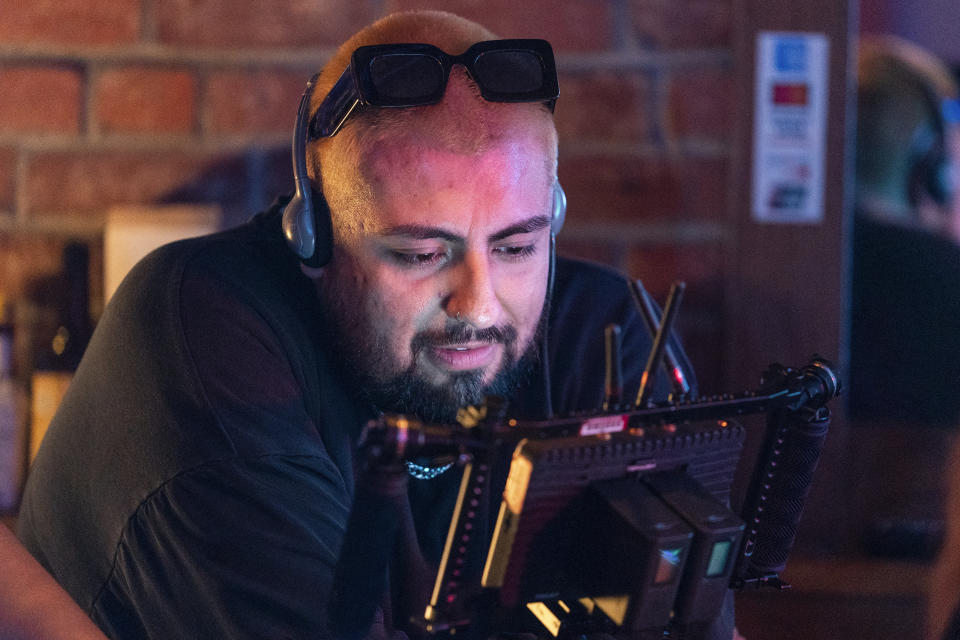 Jorge Xolalpa, a 33-year-old movie director from Mexico checks a shot on a monitor during the filming of his latest movie "Union Station" at "Trunks" gay sports bar in West Hollywood, Calif., on Tuesday, Oct. 4, 2022. Xolalpa is mired in a years-long battle over whether he can keep working legally in the United States. He is among hundreds of thousands of people waiting to learn if the program known as Deferred Action for Childhood Arrivals will be allowed to continue. (AP Photo/Damian Dovarganes)