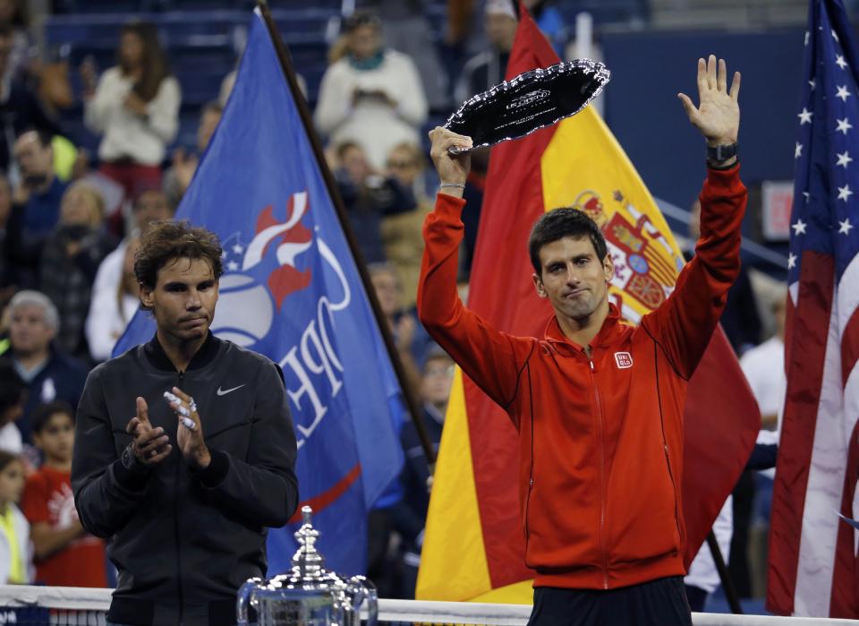 Rafael Nadal of Spain applauds as Novak Djokovic of Serbia raises his runner up trophy after Nadal won their men's final match at the U.S. Open tennis championships in New York, September 9, 2013.