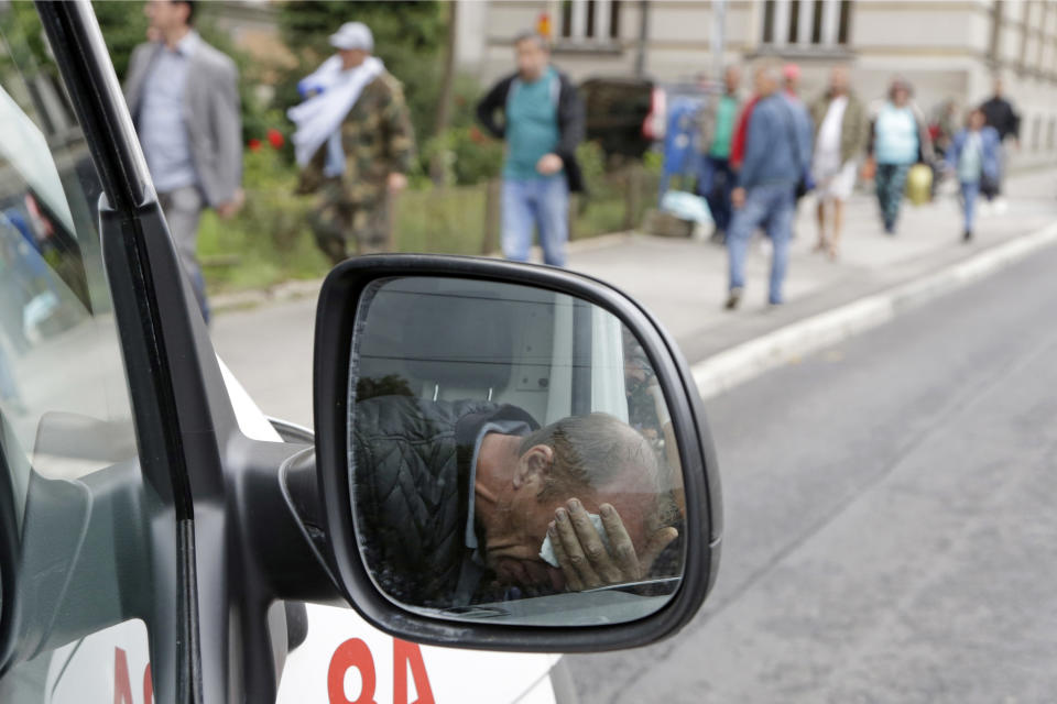 A Bosnian war veteran is seen in the side mirror of an ambulance after police used tear gas during clashes in Sarajevo, Bosnia, on Wednesday, Sept. 5, 2018. Bosnian police have clashed with several hundred protesting war veterans who are unhappy with the laws regulating their rights stemming from the 1992-95 conflict. Police with shields and helmets on Wednesday used what appeared to be pepper spray on the former fighters, some of whom were carrying flags or batons. (AP Photo/Amel Emric)