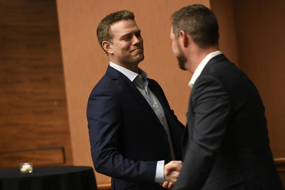 Chicago Cubs president of baseball operations Theo Epstein left, shakes hands with former Cubs pitcher Travis Wood right, during the baseball team's convention, Friday, Jan. 17, 2020, in Chicago. (AP Photo/Paul Beaty)