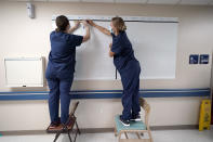 Registered nurses Army Capt. Rachel Curtis, right, and Capt. Christa Angelotti, with the Urban Augmentation Medical Task Force, sets up a patient board inside a wing at United Memorial Medical Center, Thursday, July 16, 2020, in Houston. Soldiers will treat COVID-19 patients in the newly setup hospital wing as Texas receives help from across the country to deal with its coronavirus surge. (AP Photo/David J. Phillip)