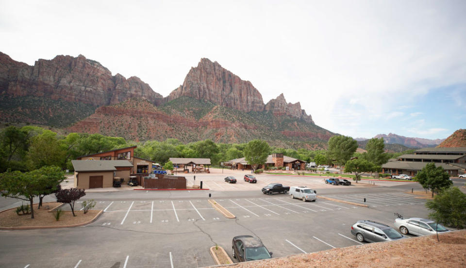 A few cars are parked in the normally filled parking lot outside the walk up entrance to Zion National Park.