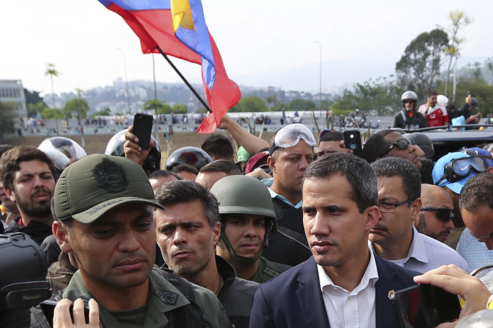 ADDS IDENTIFICATION OF SOLDIER - Venezuela's opposition leader and self-proclaimed president Juan Guaidó, center right, flanked by activist Leopoldo López, center left, stands with National Guard Lieutenant Colonel Ilich Sanchez, who is helping to lead a military uprising, as they talk to the press and supporters outside La Carlota air base in Caracas, Venezuela, Tuesday, April 30, 2019. Guaidó took to the streets with Lopez and a small contingent of heavily armed troops early Tuesday in a bold and risky call for the military to rise up and oust Maduro. (AP Photo/Fernando Llano)